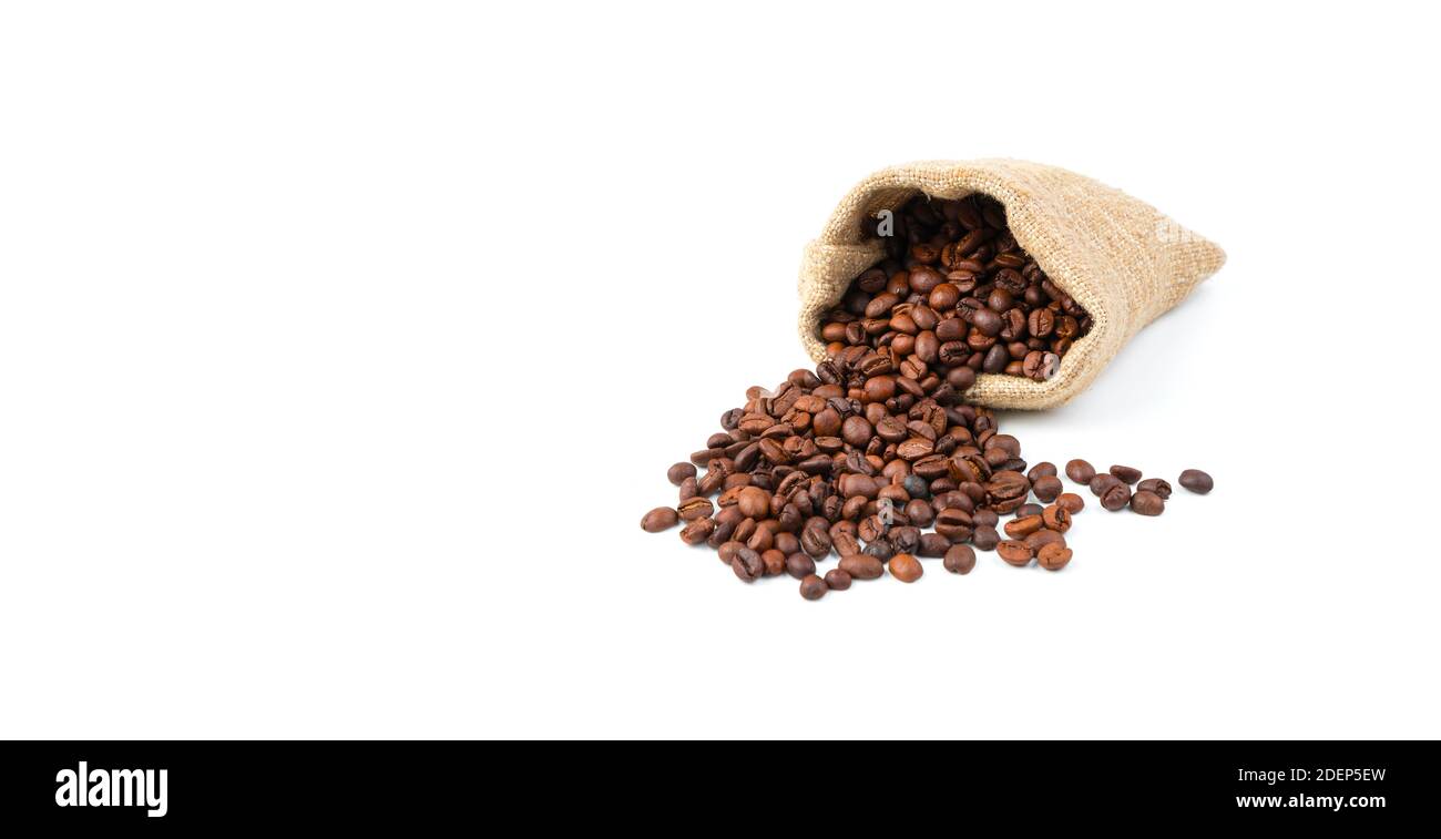Renverser des grains de café dans un sac de lin isolé sur un fond blanc. Banque D'Images