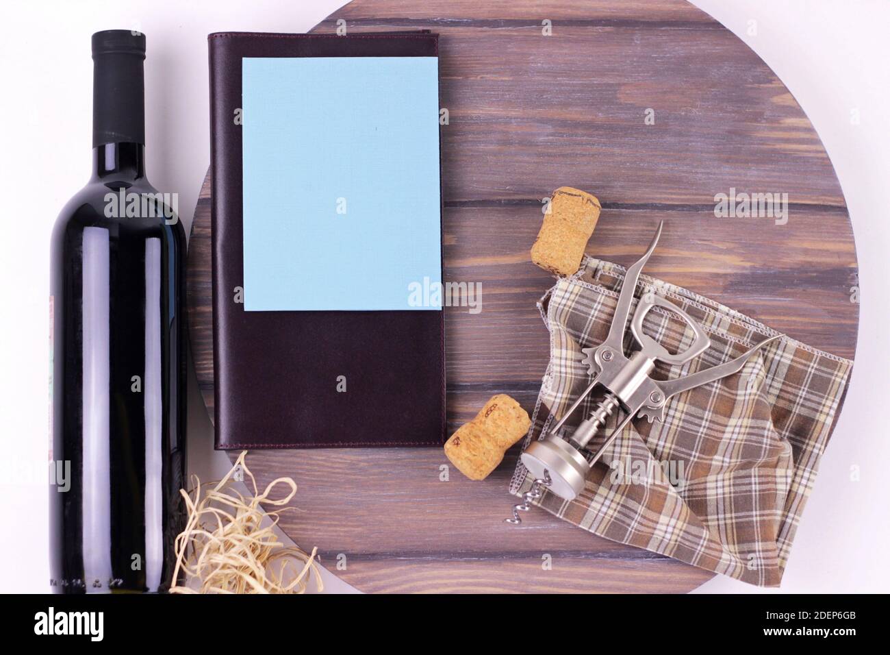 Tire-bouchon, bouchons, bouteille de vin et carte de menu vierge sur le vieux tonneau vue rapprochée.maquette de menu vide sur plaque ronde en bois sombre isolée. Banque D'Images