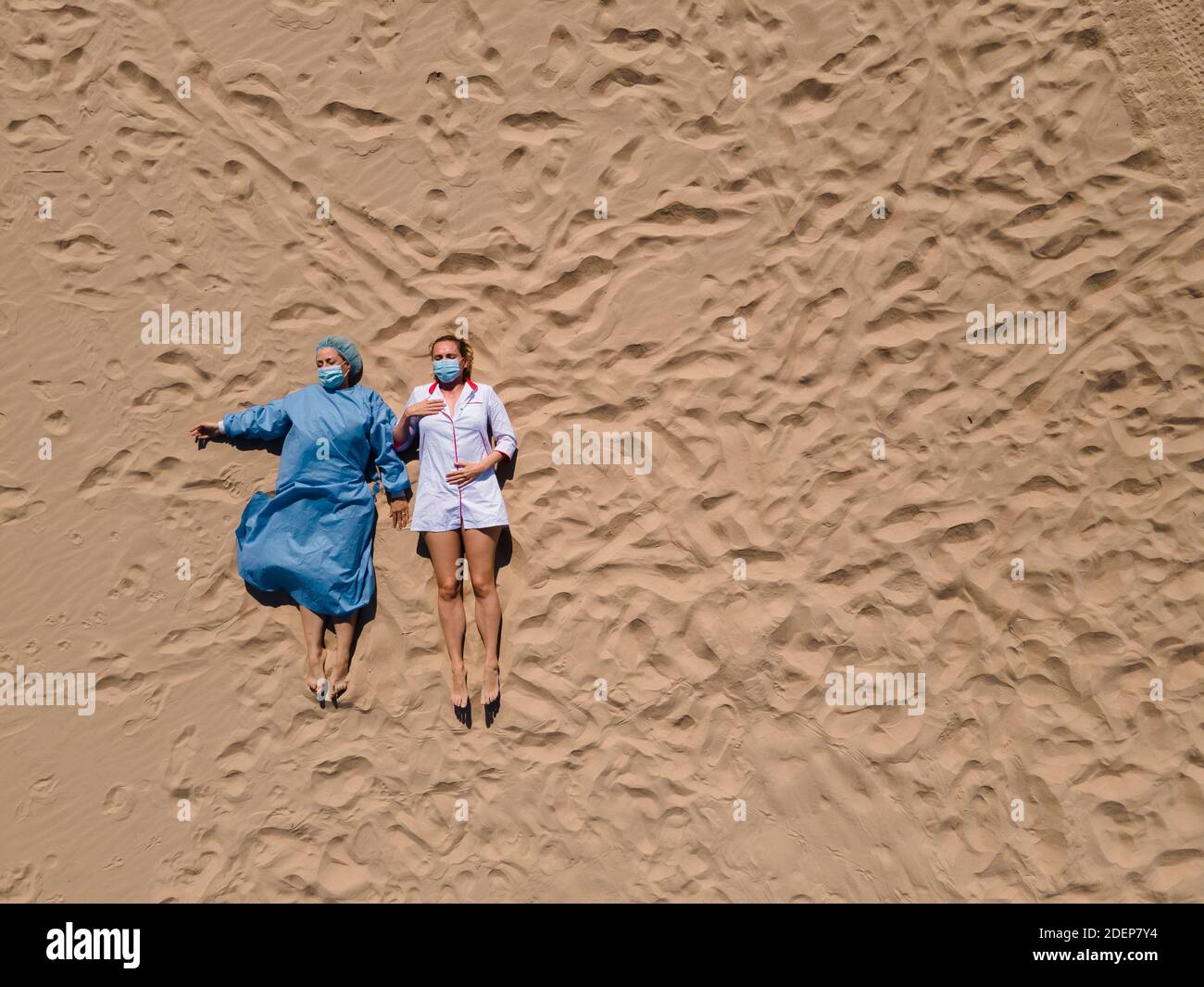 Absurde: Deux femmes médecins dans l'équipement médical allongé sur le sable se sentant et fatigué Banque D'Images