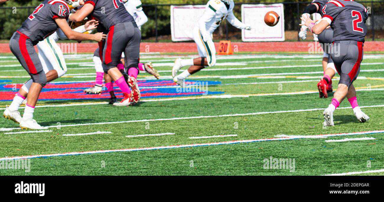 Quarterback Laterback lancer le football à son dos de course tandis que la ligne offensive bloque suring un match de football. Banque D'Images
