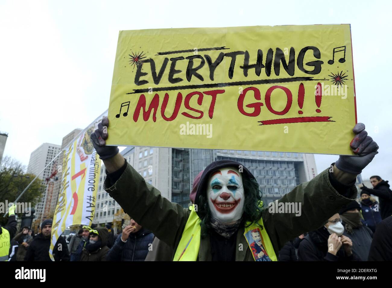 Gilet jaune (gilets jaunes) le manifestant portant le maquillage du  personnage DC comic Joker tient une bannière sur la place d'Italie à Paris,  lors d'affrontements sur les coulisses d'une manifestation marquant le