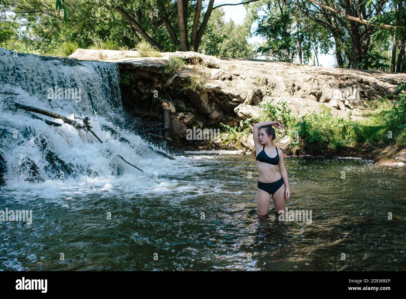 Portrait de jeune fille debout dans le genou rivière profonde près une cascade Banque D'Images