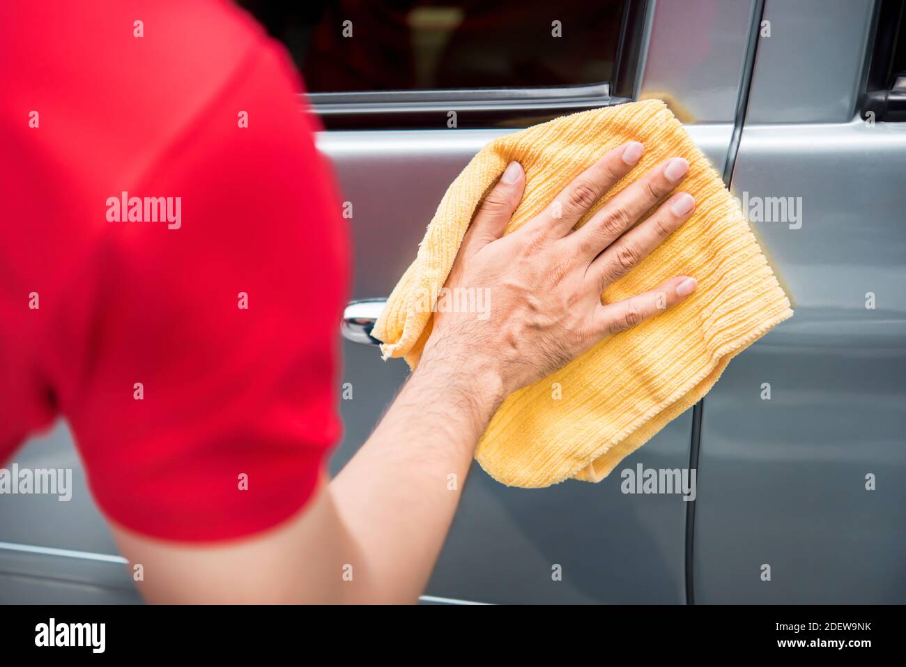 Le personnel du service d'entretien automobile pour hommes nettoie la porte de la voiture avec une microfibre tissu Banque D'Images