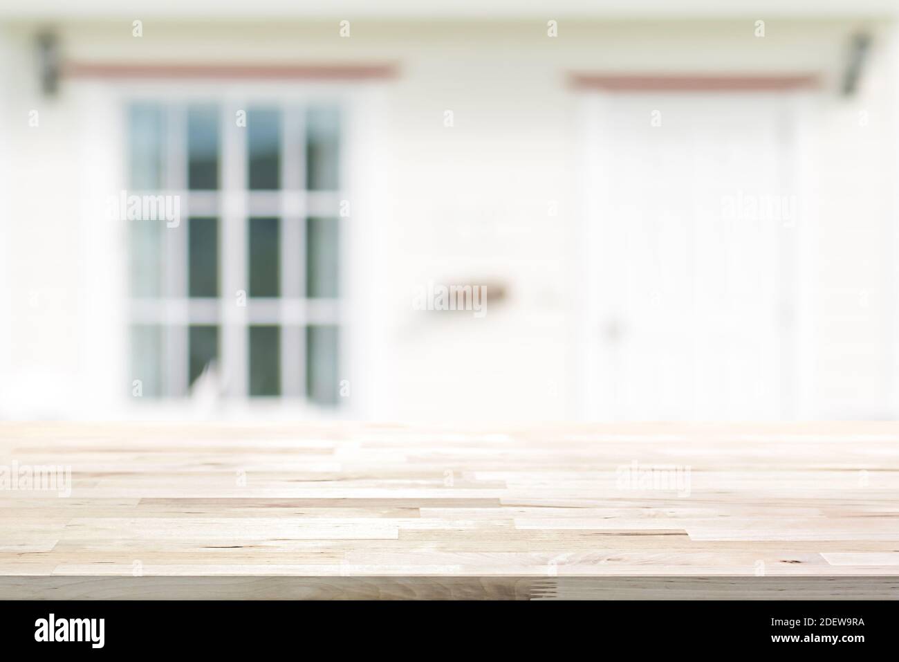 Plan de table en bois sur la façade de maison blanche floue avec porte et fenêtre en verre - peut être utilisé pour l'affichage ou montage de vos produits Banque D'Images