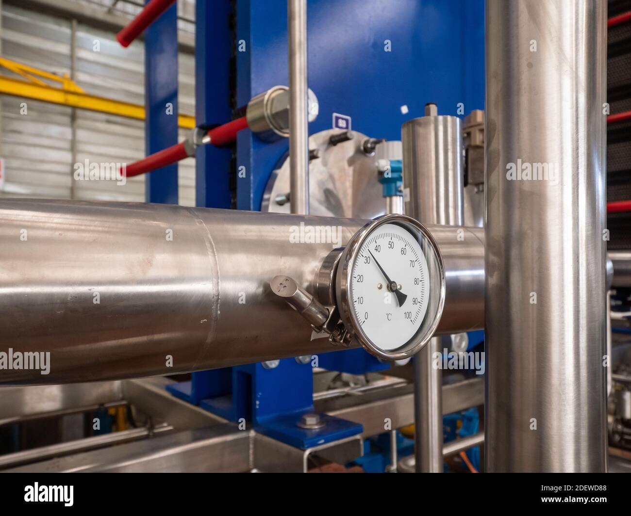 Thermomètre industriel sur un tuyau en acier inoxydable dans un atelier industriel. Échangeur thermique de plaque en arrière-plan Banque D'Images