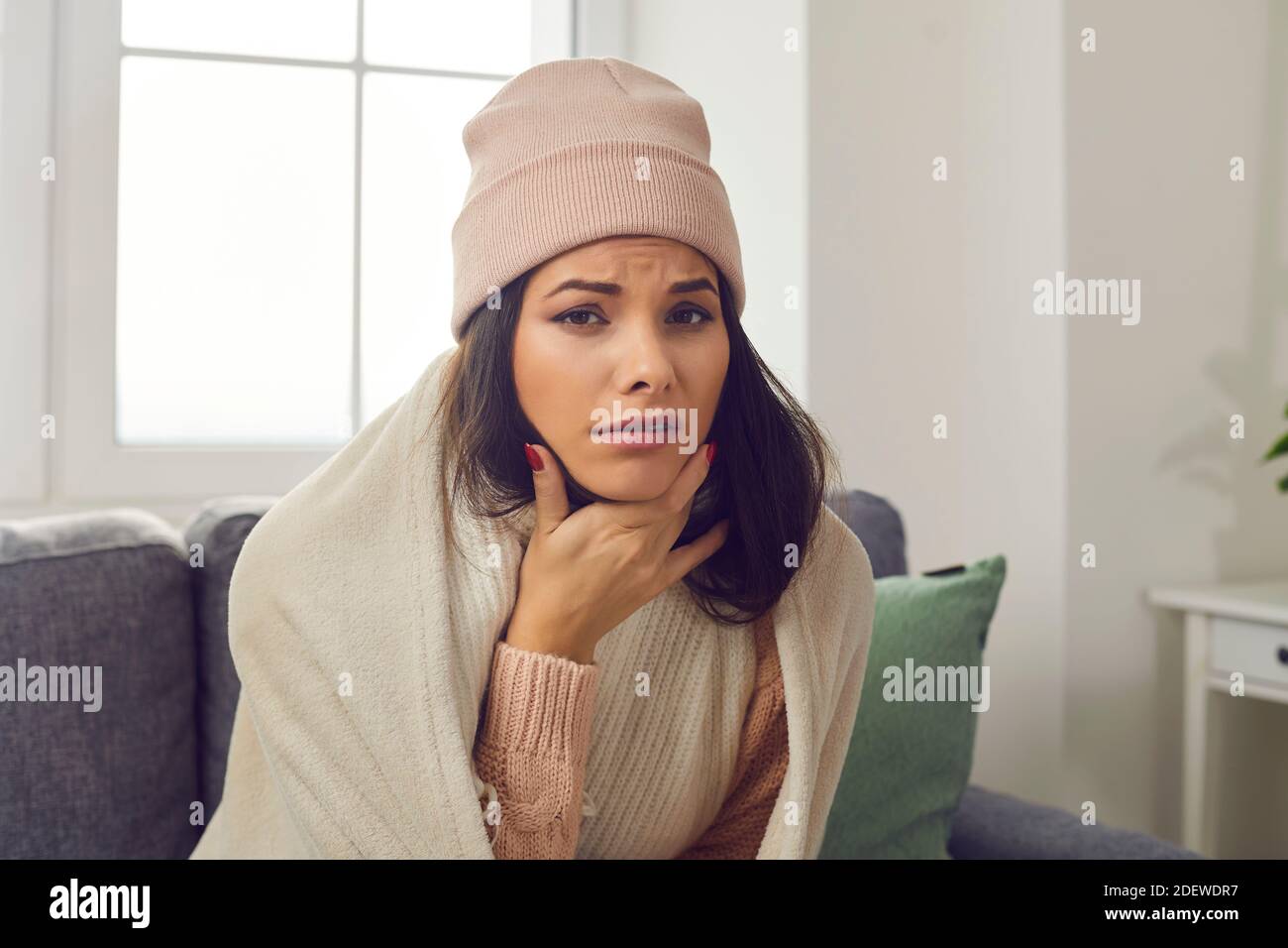 Malheureuse malade jeune femme dans des vêtements chauds souffrant de la grippe et se plaindre du mal de gorge Banque D'Images