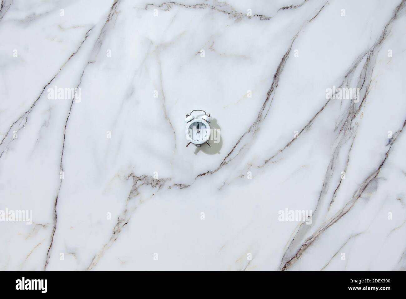 Vue de dessus du réveil blanc sur minuit ou douze sur blanc Banque D'Images