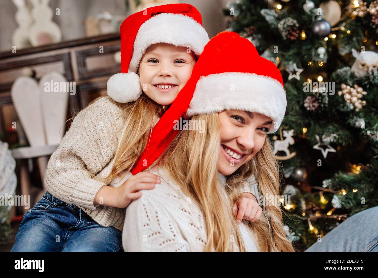 Portrait de la mère heureuse au père noël et de la fille près de l'arbre de noël à la maison. Joyeux Noël Banque D'Images