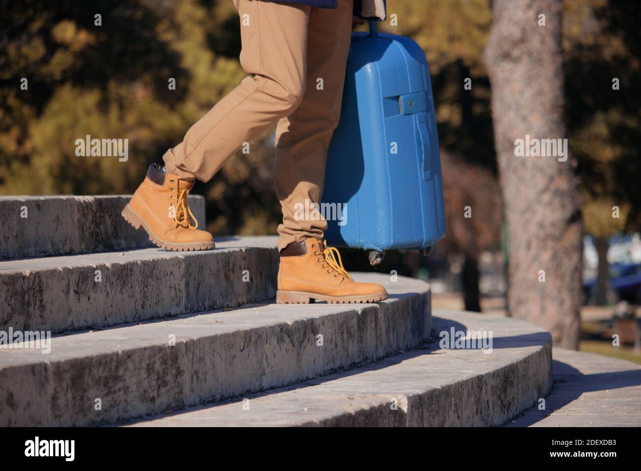 Gros plan d'un jeune homme méconnaissable descendant des escaliers dans la rue avec sa valise dans la main, fatigué après un long voyage. Voyage d'affaires 2021. Banque D'Images