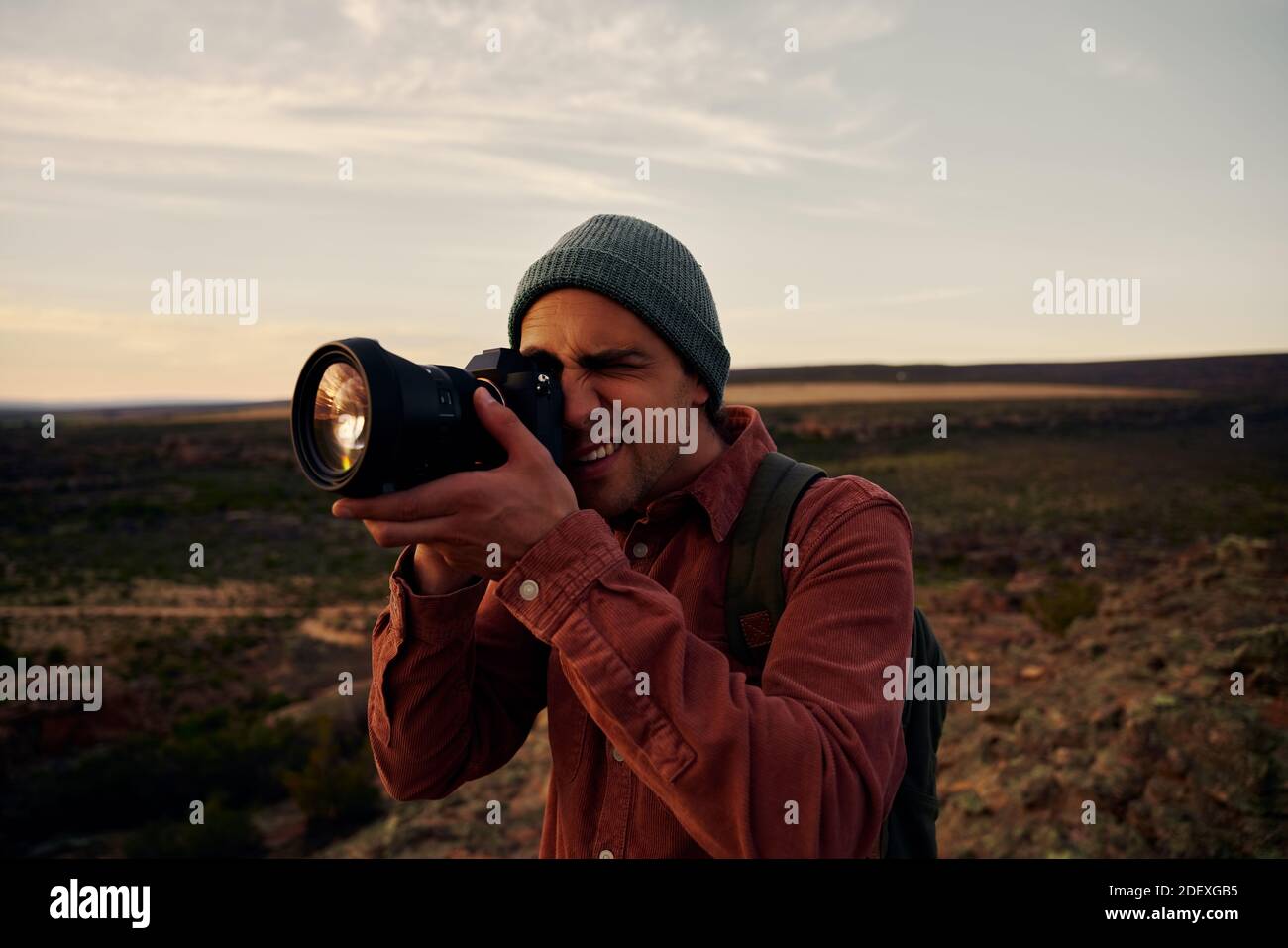 Portrait de jeune randonneur mâle prenant des photos de montagnes et magnifique lever de soleil avec un appareil photo professionnel Banque D'Images