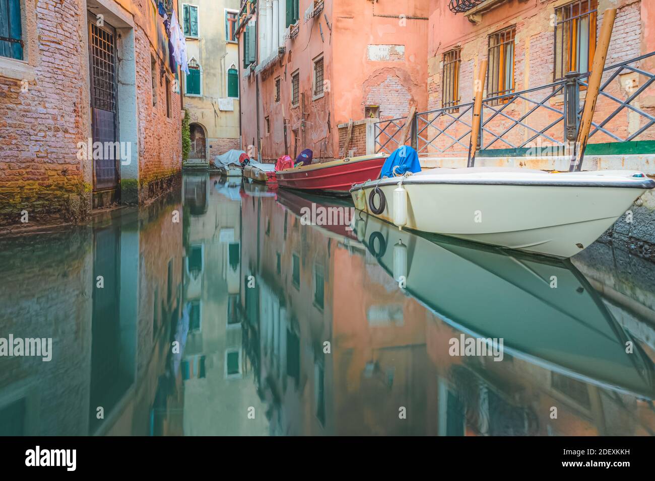 Les bateaux se reposent tranquillement sur un canal vert émeraude tôt dans Le matin à Venise Banque D'Images