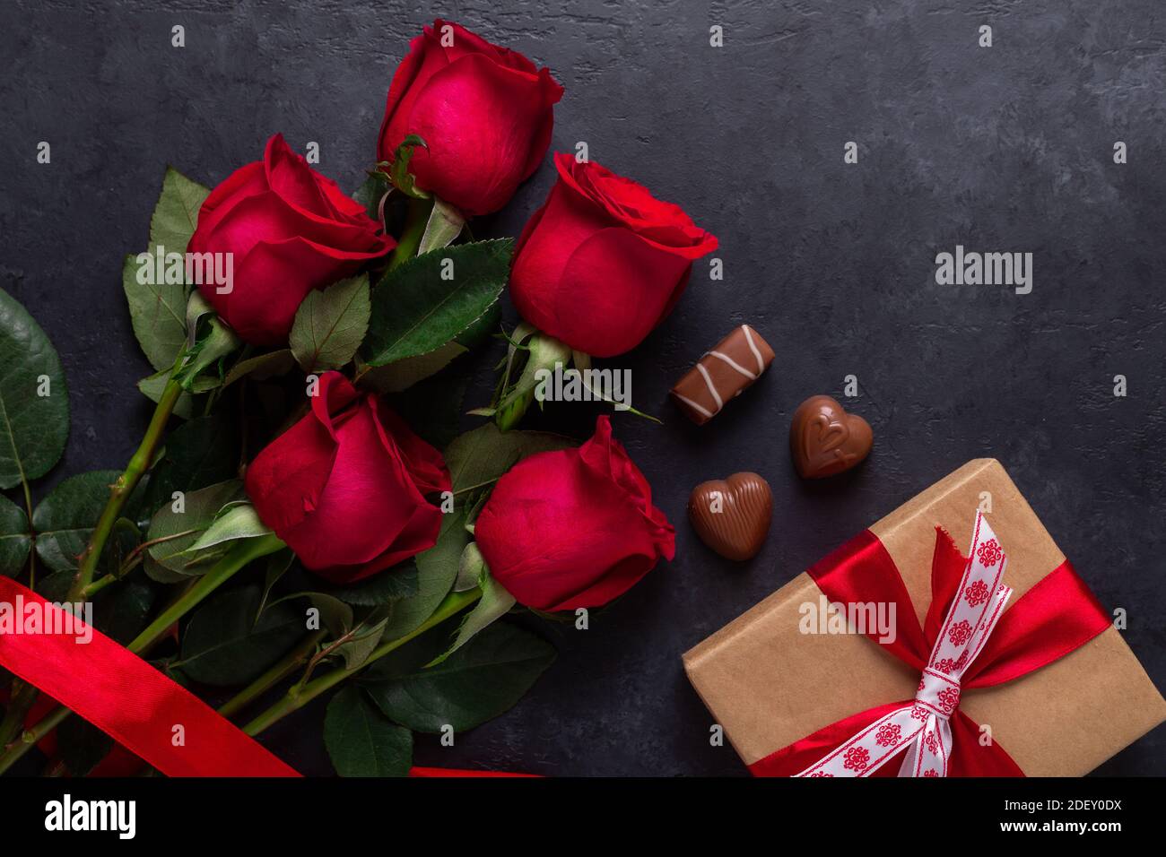 Bouquet de fleurs roses rouges, boîte-cadeau, bonbons au chocolat sur fond  de pierre noire carte de vœux de Saint-Valentin espace de copie plat Photo  Stock - Alamy