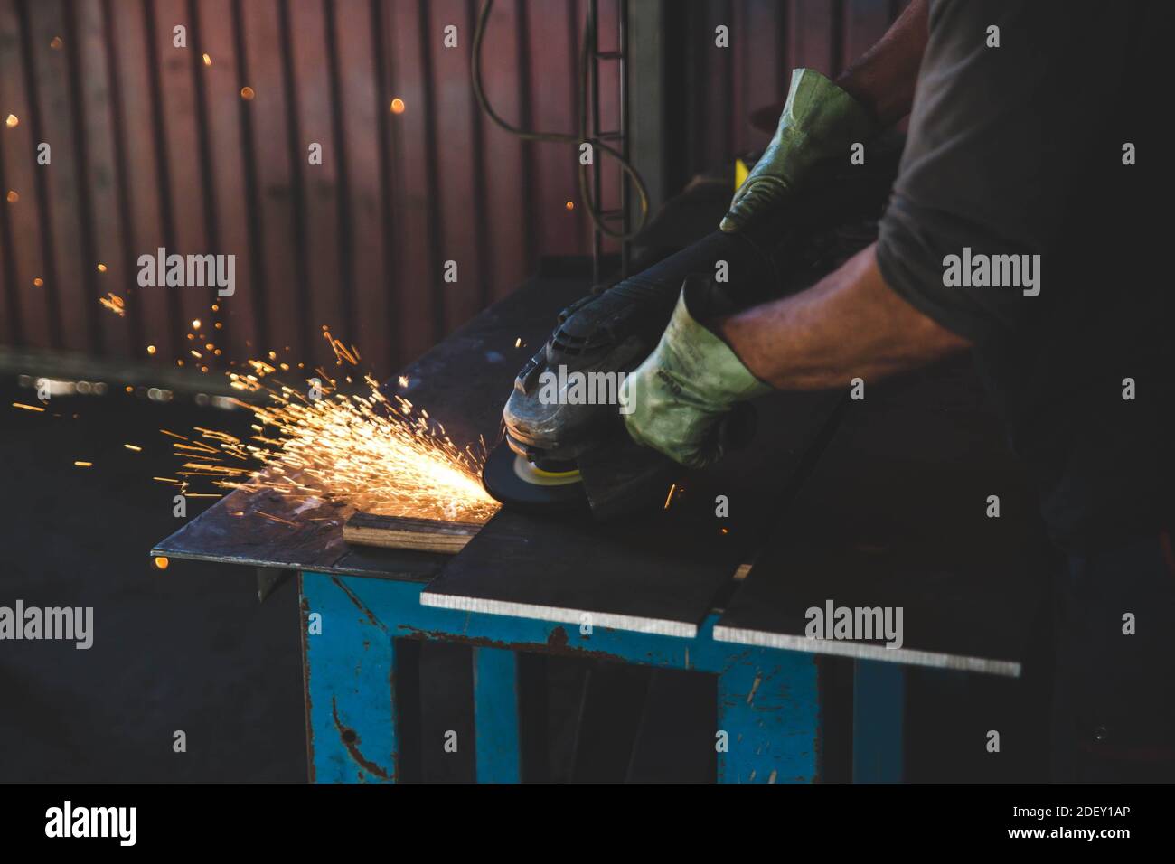 Un homme utilisant une meuleuse d'angle couper la roue à coupe la plaque métallique avec une douche d'étincelles Banque D'Images