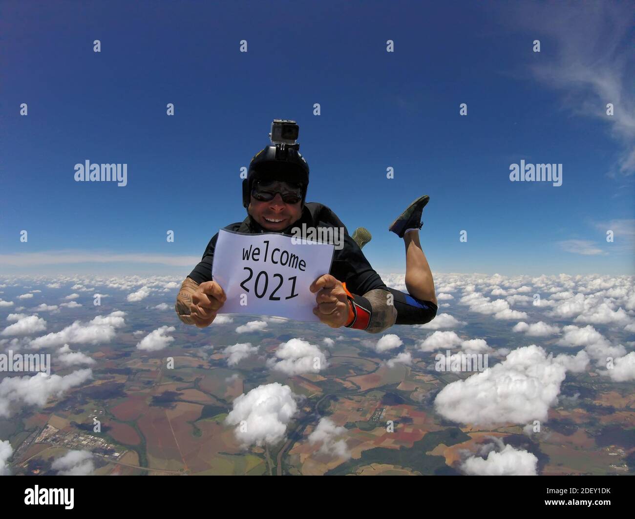 Parachutiste souriant portant un signe écrit: Bienvenue 2021. Banque D'Images