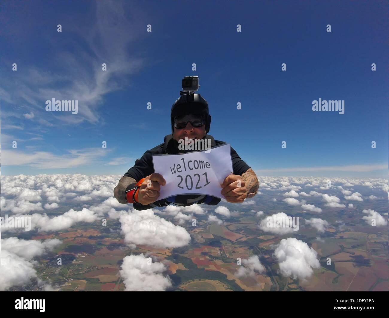 Parachutiste souriant portant un signe écrit: Bienvenue 2021. Banque D'Images