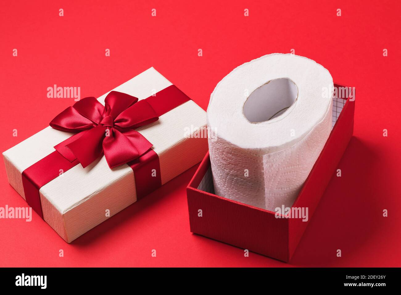 Rouleau de papier toilette dans une boîte cadeau sur fond rouge. Banque D'Images