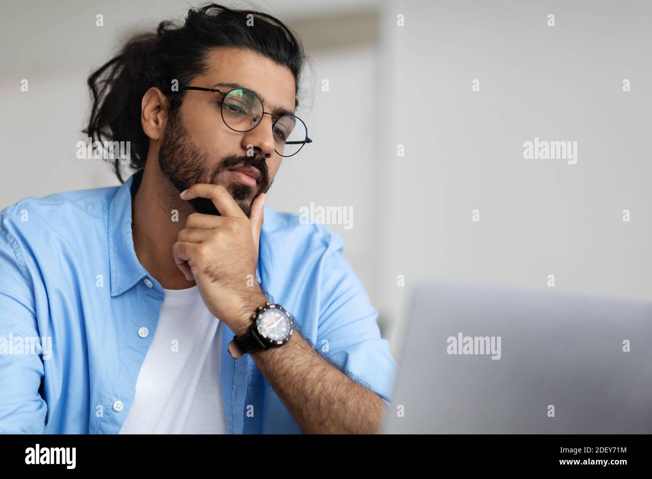 Gros plan Portrait de l'Indien Guy de handsome focalisé dans le travail de lunettes Sur ordinateur portable Banque D'Images