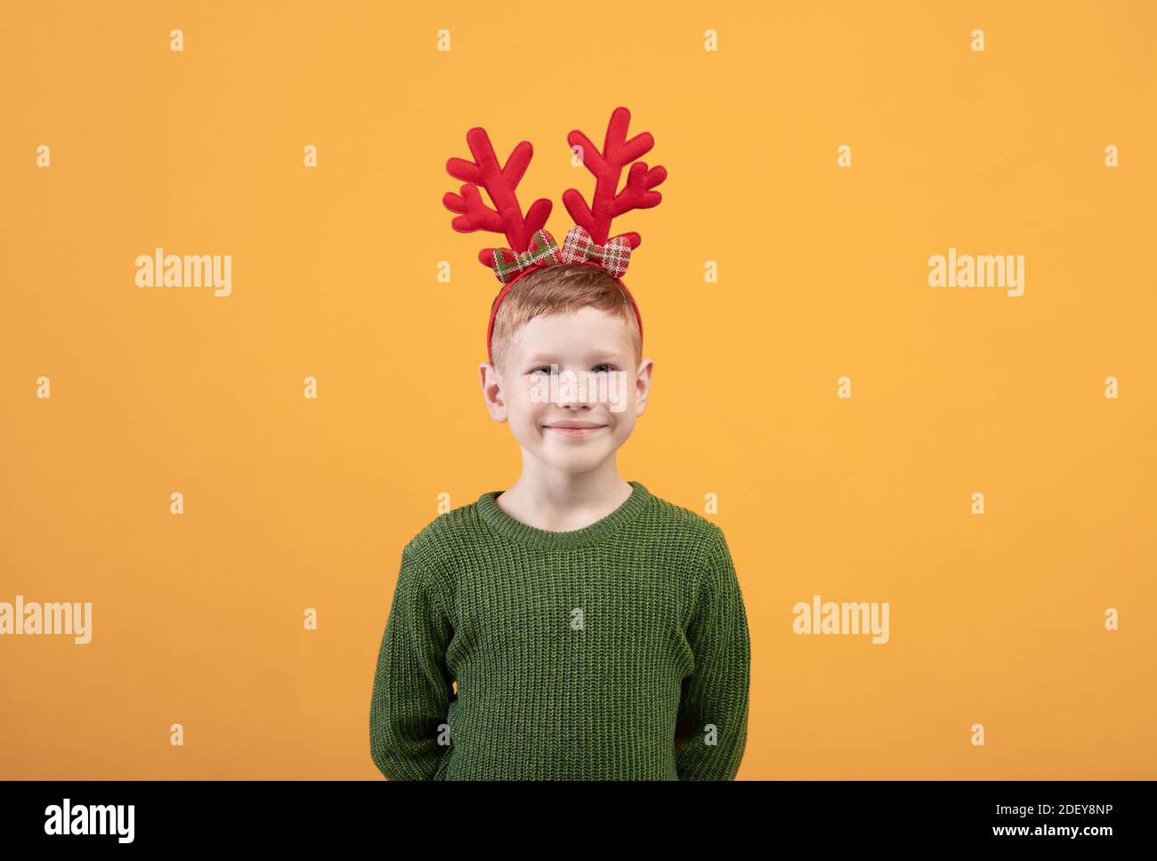 Adorable enfant en vert chandail d'hiver posé sur jaune Banque D'Images