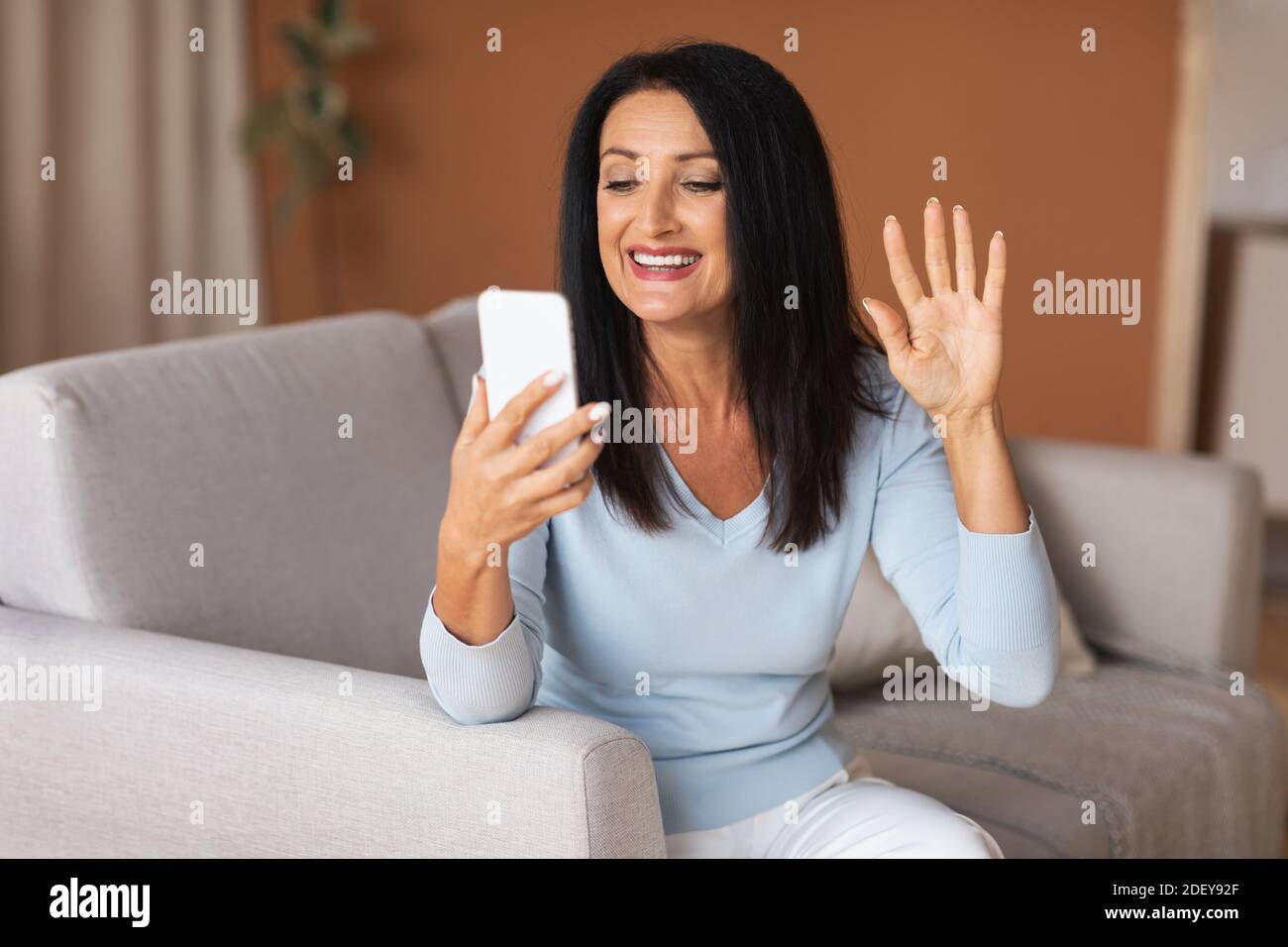 Bonne femme utilisant un téléphone portable pour les appels vidéo et les ageuses Banque D'Images