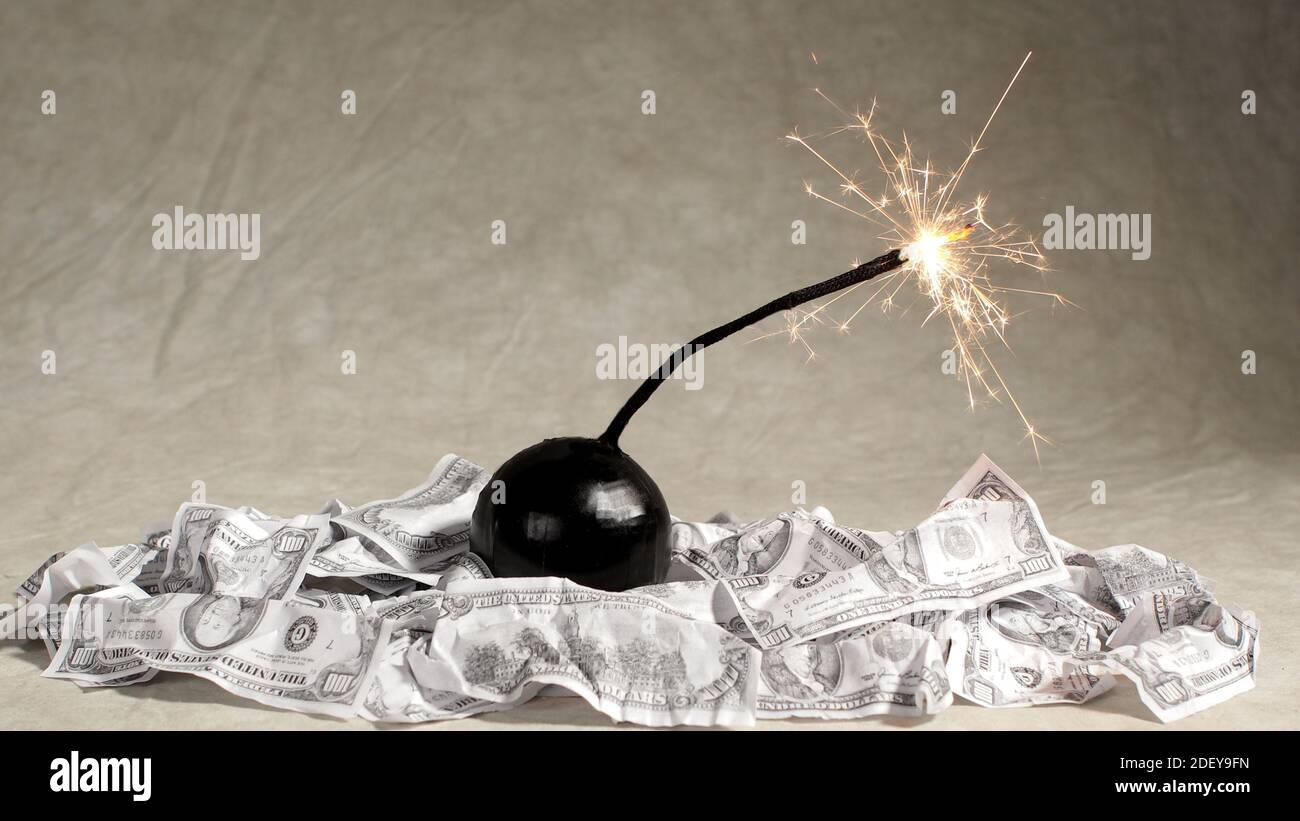 Une bombe avec un fusible allumé se trouve sur une pile de billets de 100 dollars. Banque D'Images