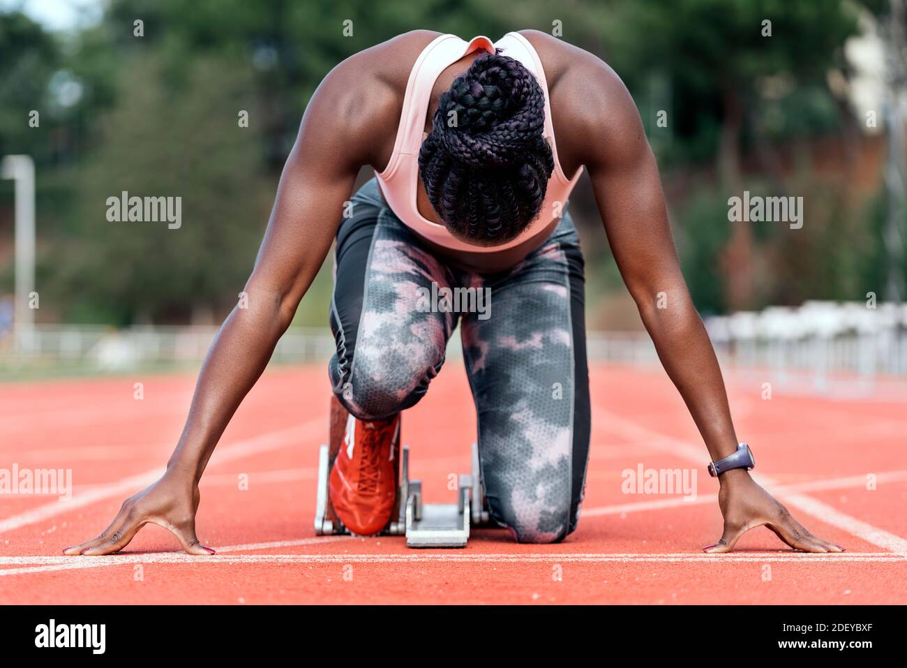 Photo d'un sprinter afro-américain méconnaissable en position de départ pour commencer à courir sur un circuit d'athlétisme Banque D'Images