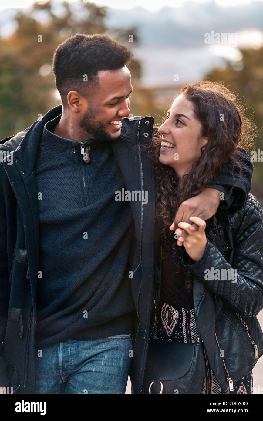 Photo de stock du moment heureux de couple interracial d'amoureux regardant les uns les autres. Ils sont à Madrid Banque D'Images