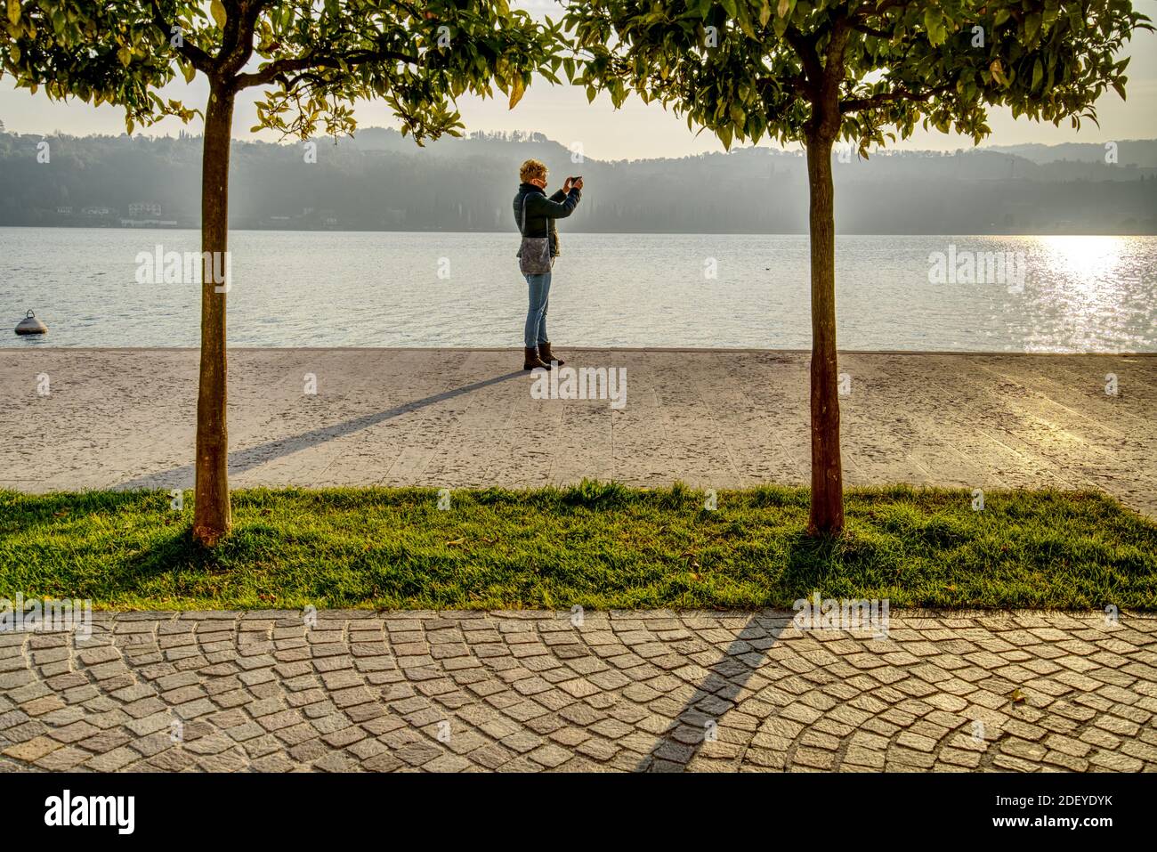 Une femme de race blanche d'âge moyen qui a tiré un selfie debout Sur la rive du lac de Garde dans la ville de Salo En Italie à l'automne 2020 Banque D'Images