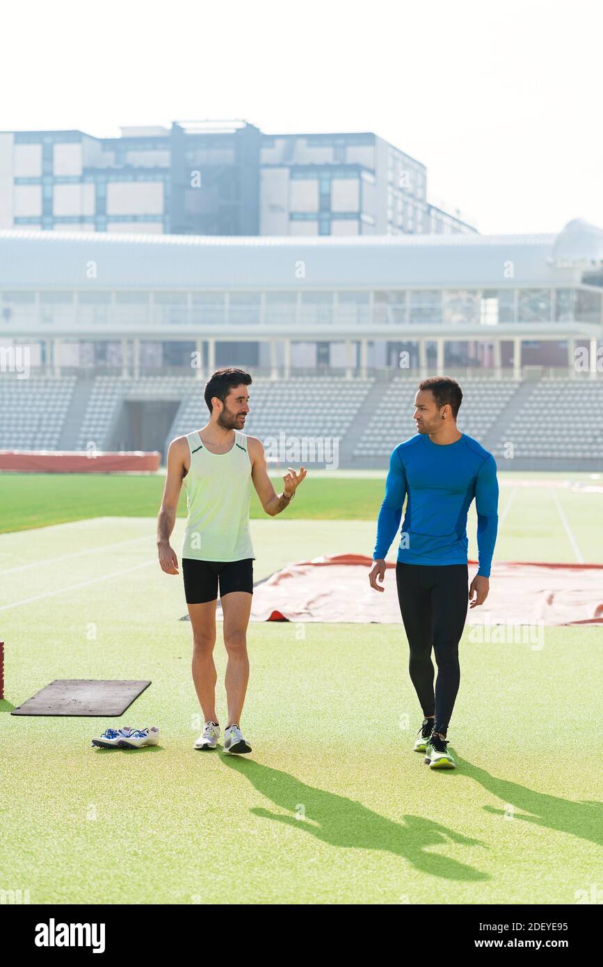 Photo de deux amis athlètes portant des vêtements de sport bavardant et marchant sur une piste de sport. Banque D'Images
