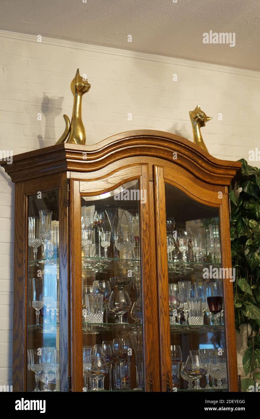 Un gros plan d'un tombeau commode en bois plein de vintage verres avec deux statues de chat sur le dessus de la chambre Banque D'Images