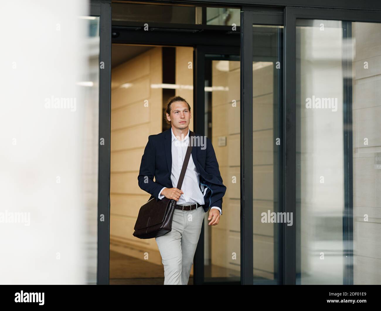 Homme d'affaires sortant de l'immeuble de bureaux par des portes automatiques Banque D'Images