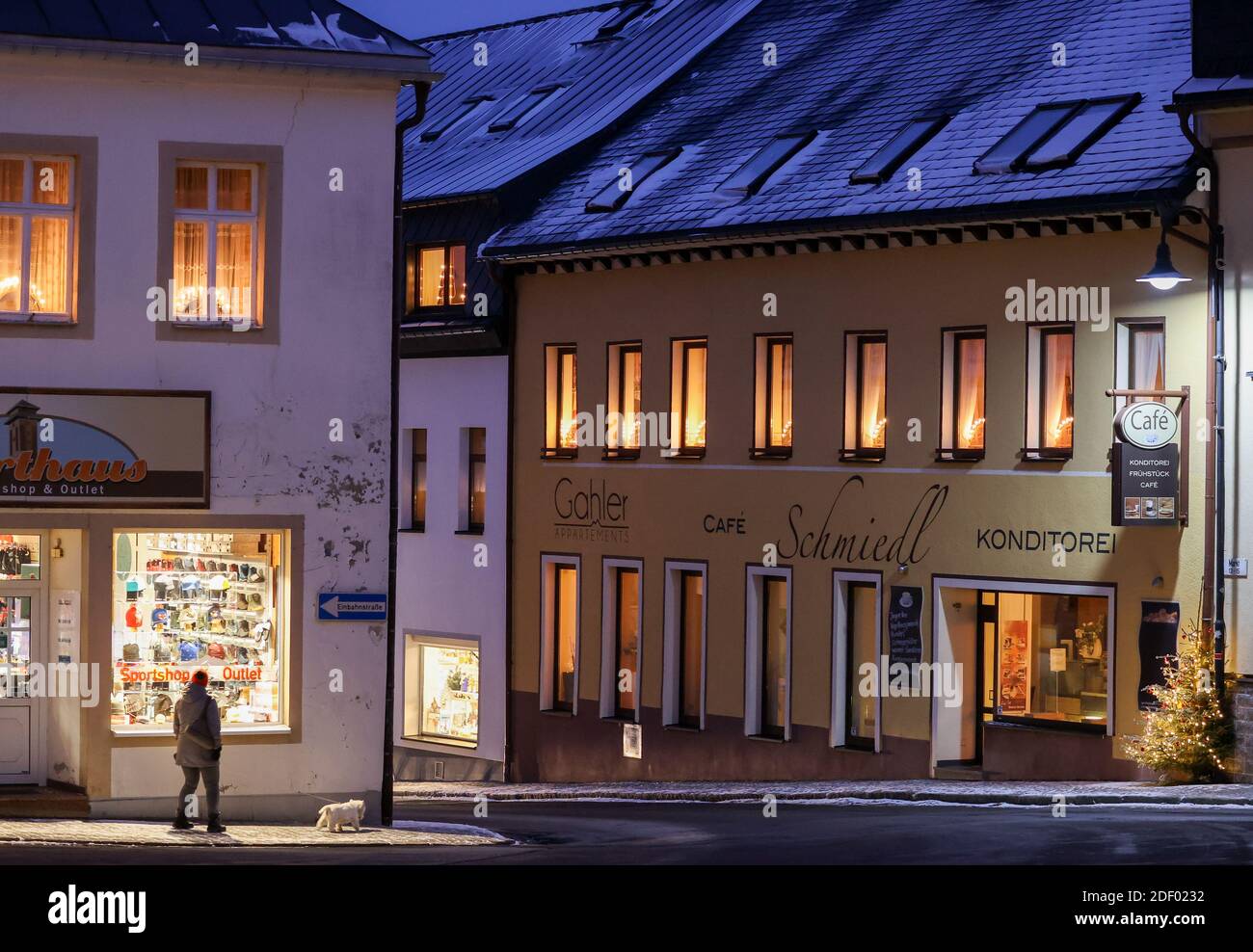 Oberwiesenthal, Allemagne. 02e décembre 2020. Une femme marche avec son chien devant une fenêtre illuminée dans une rue déserte. Dans aucun autre État fédéral, la pandémie de Corona ne se propage actuellement aussi rapidement qu'en Saxe. Par conséquent, des mesures plus strictes sont maintenant en place, y compris des restrictions de sortie. Credit: Jan Woitas/dpa-Zentralbild/dpa/Alay Live News Banque D'Images