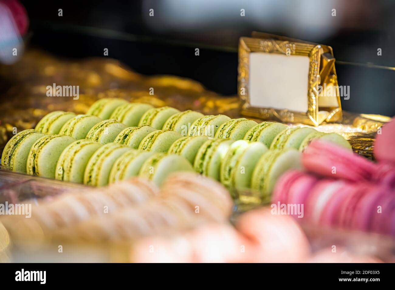 Exposition de macarons roses et verts haut en couleur tablette à fenêtre dans la boutique de boulangerie Banque D'Images
