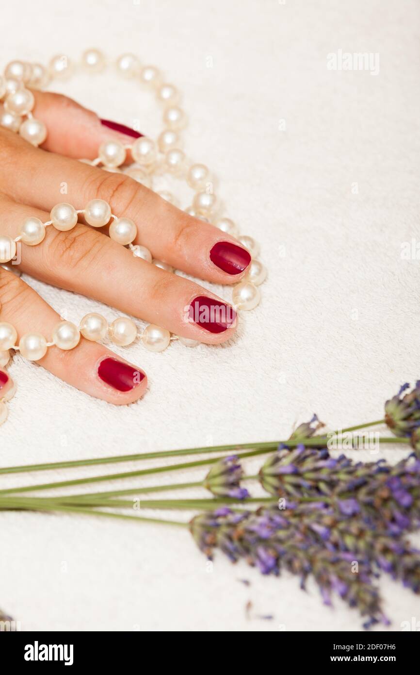 Les mains d'une femme avec des vernis à ongles rouge posé par l'esthéticienne Banque D'Images