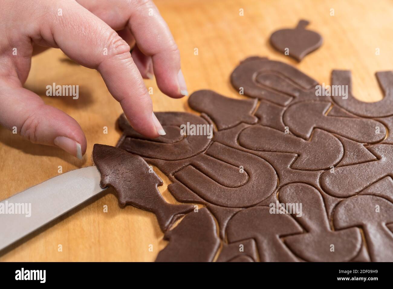 Couper les biscuits de pain d'épice de pâte brute roulée. Pâtisserie traditionnelle douce de Noël ou du nouvel an. La main femelle porte une confestion en forme de poisson. Banque D'Images