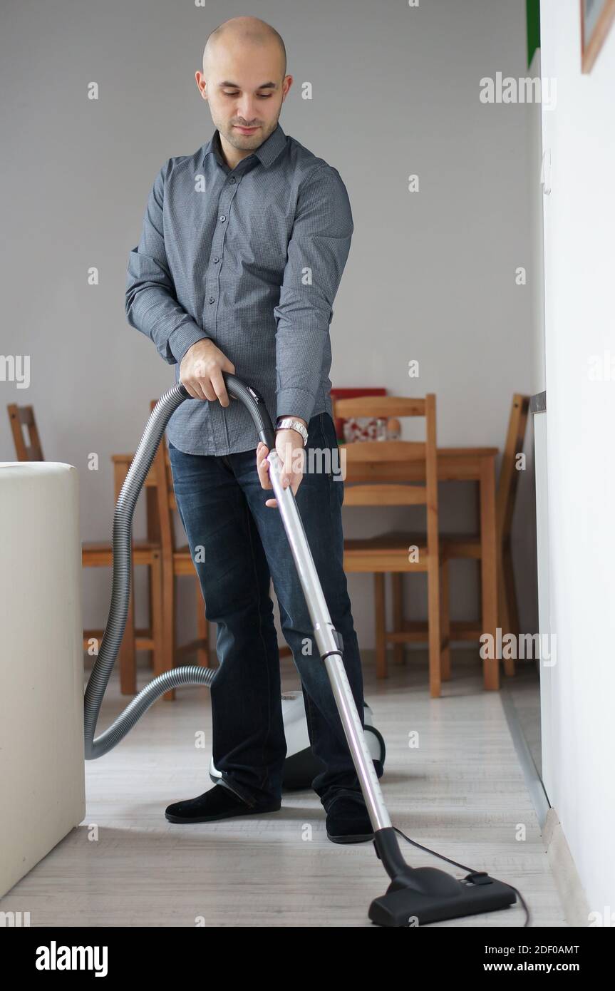 Un cliché vertical d'un homme nettoyant le sol avec un aspirateur sous les lumières d'une maison Banque D'Images