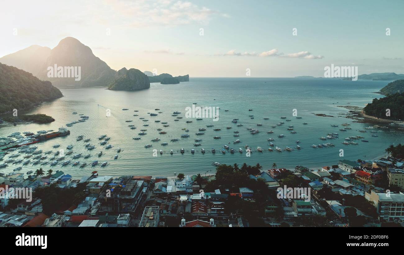 Lever du soleil à la ville portuaire avec silhouette de montagne. Transport maritime dans un paysage urbain tropical au soleil de l'été. Ville paradisiaque avec des bâtiments au lever du soleil. Bord de mer avec des navires, des bateaux à l'île des Philippines Banque D'Images