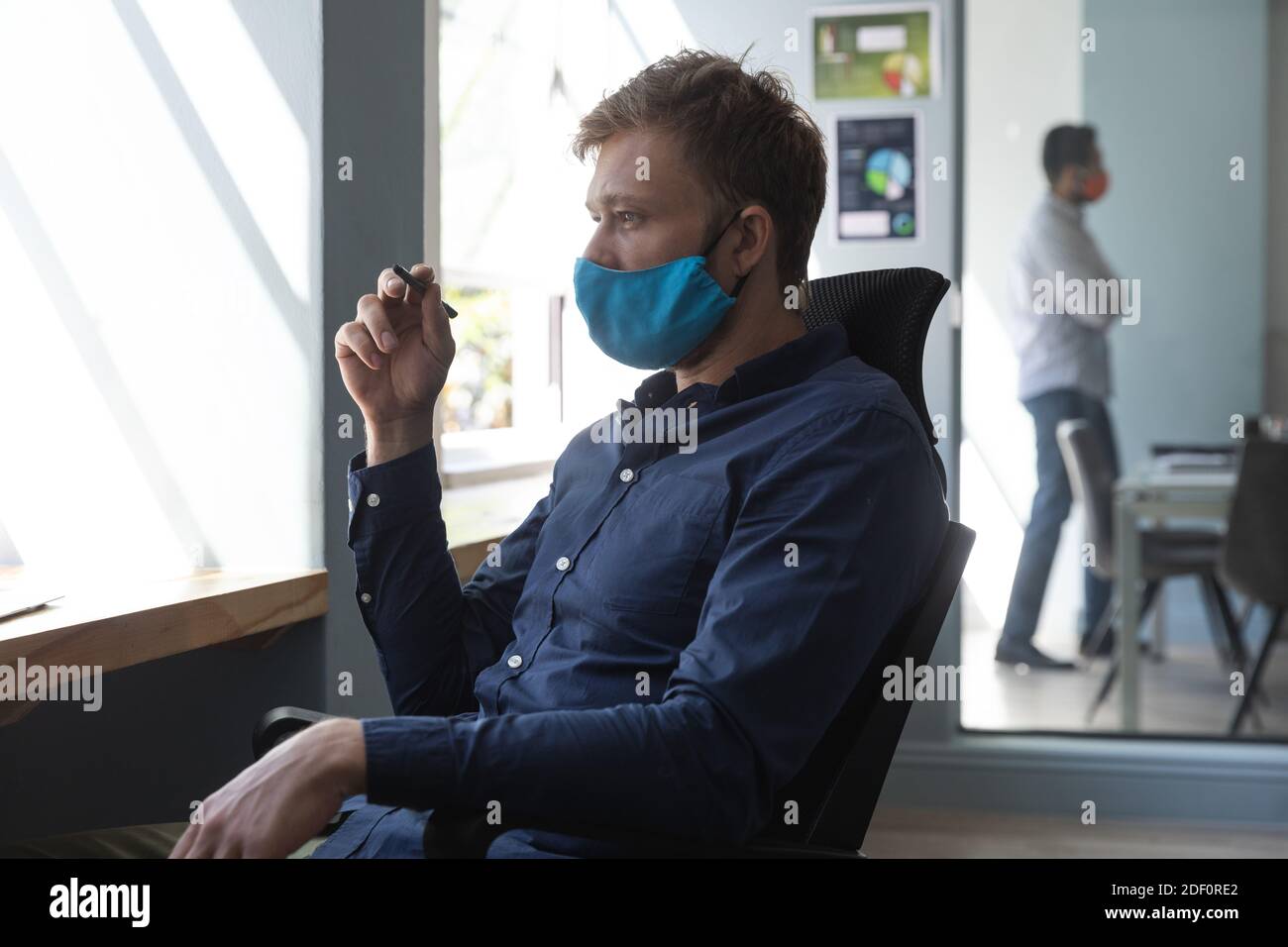 Homme caucasien portant un masque dans un bureau Banque D'Images