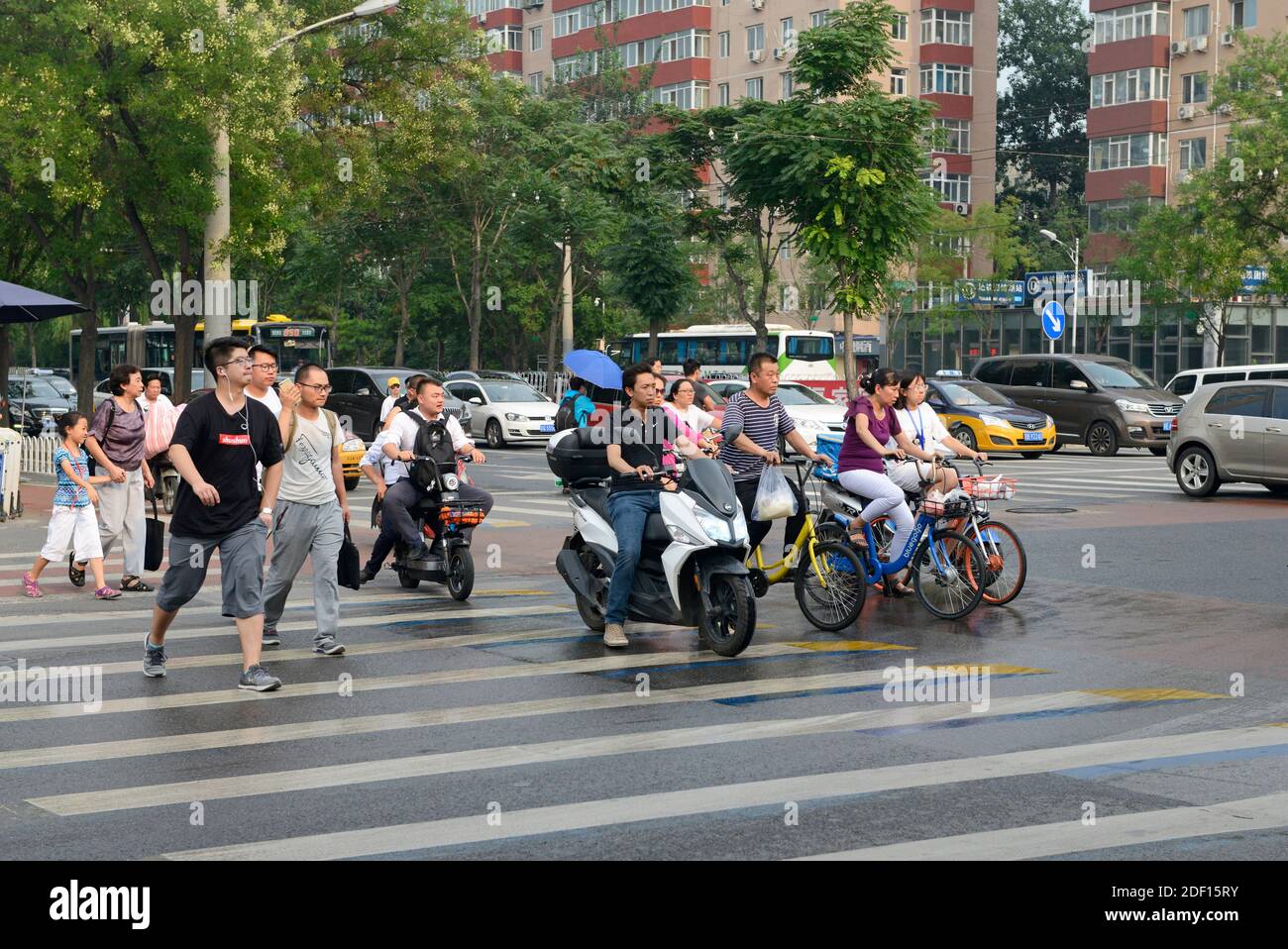 Les gens traversent une rue une fois que les lumières changent de vert après une douche de pluie dans le quartier de Chaoyang, Beijing, Chine Banque D'Images