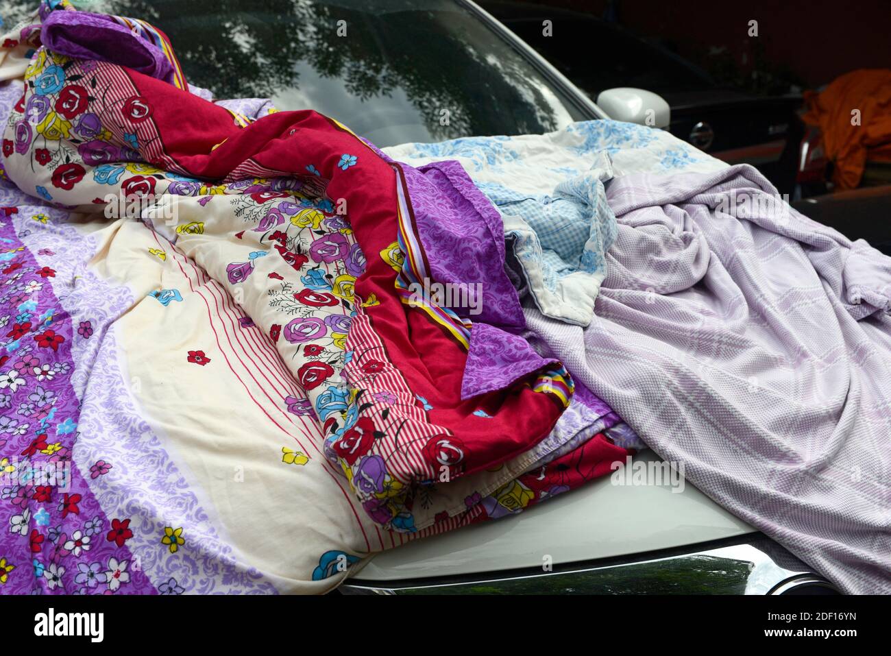 Un capot de voiture recouvert de vêtements et de couvertures dans l'ouest de Beijing, en Chine Banque D'Images