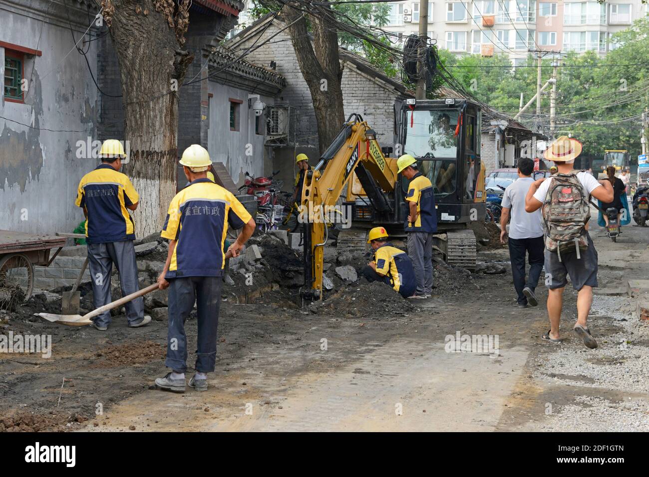 Une équipe de travailleurs fait surface à une route hutong dans le centre-ouest de Beijing, en Chine, alors que les piétons se promeunaient. Banque D'Images