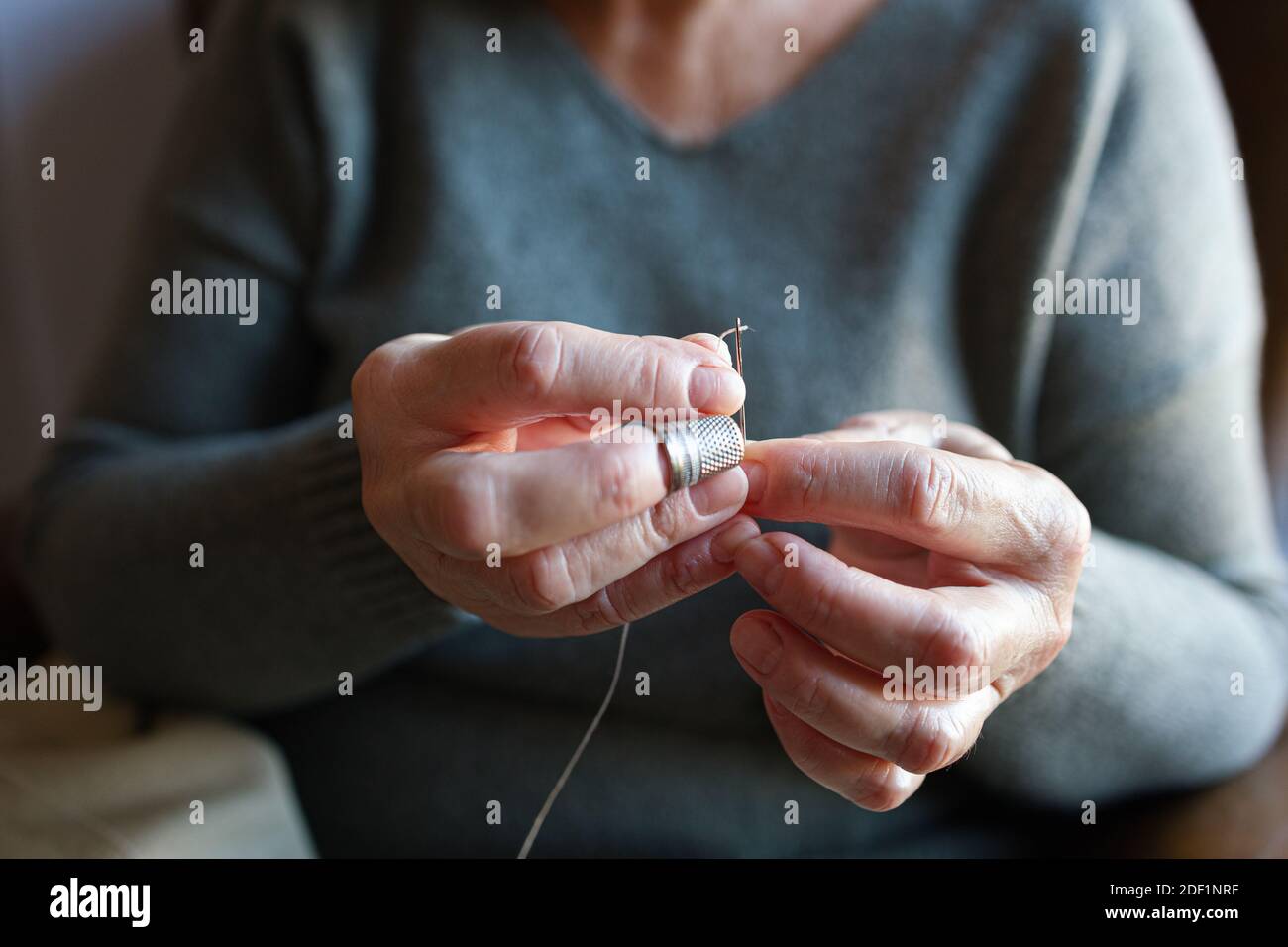 Vieille femme filant une aiguille Banque D'Images