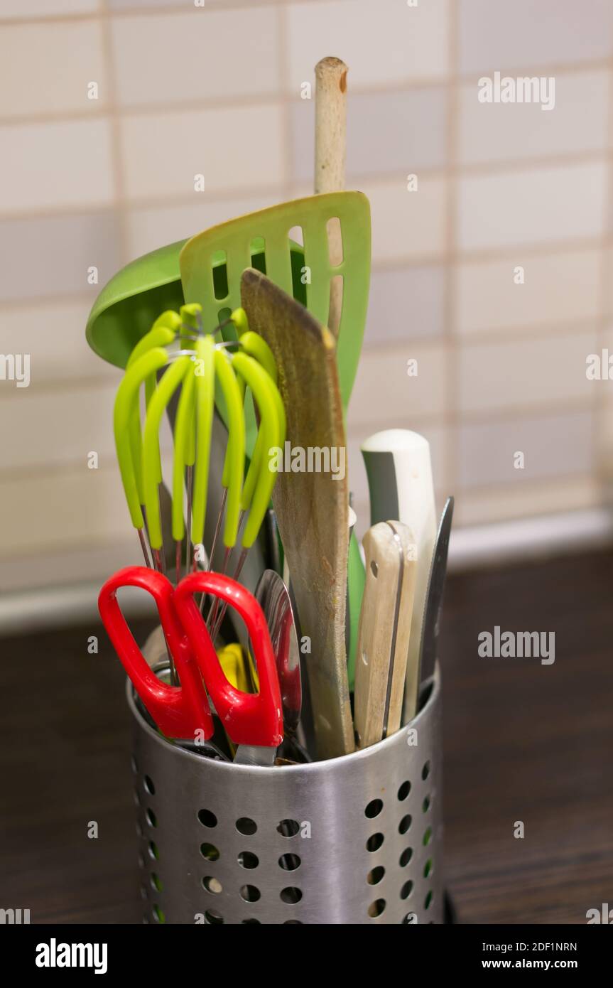 Un cliché vertical de ciseaux, spatules et autres outils de cuisine dans un récipient Banque D'Images
