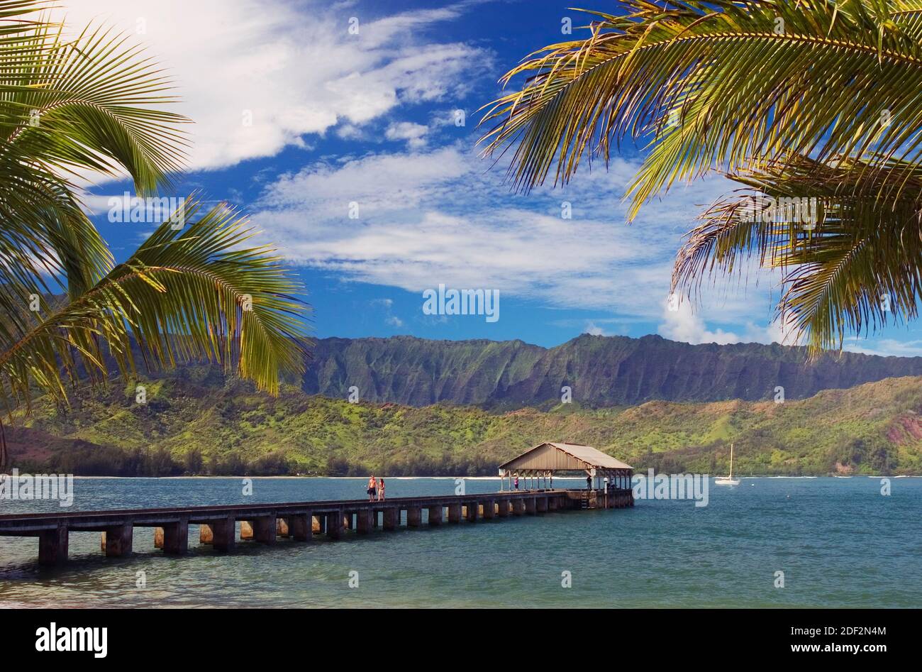 Hanalei Bay, Kauai, Hawaii, avec un couple sur la jetée et un voilier ancré dans la baie. Banque D'Images