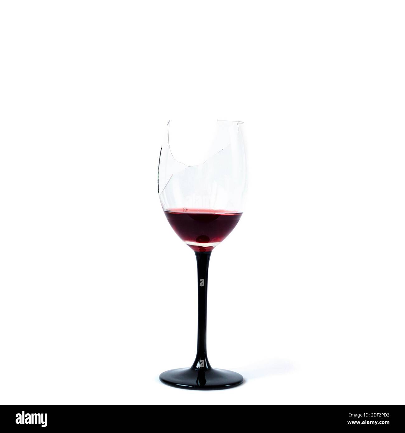 Verre de vin cassé avec des restes de vin rouge isolés sur fond blanc. Banque D'Images