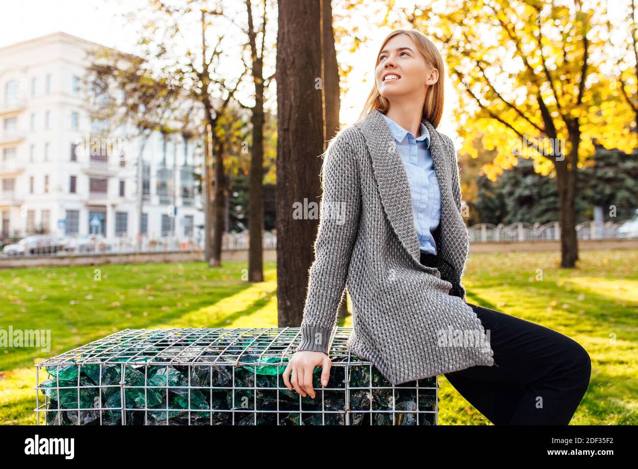 jeune femme assise sur un banc de parc et rires. belle fille de bonne humeur, un jour d'automne, appréciant le bon temps. Banque D'Images