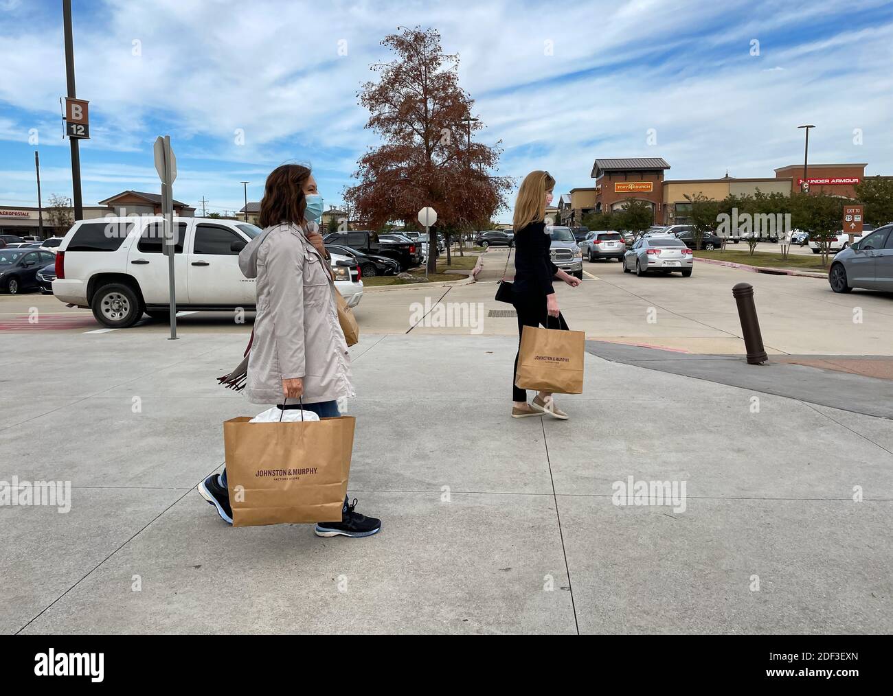 Allen, TX / USA - 27 novembre 2020 : vue rapprochée des personnes portant le masque et portant les sacs de shopping marchant dans les magasins d'usine Allen Premium Outlets sur B Banque D'Images