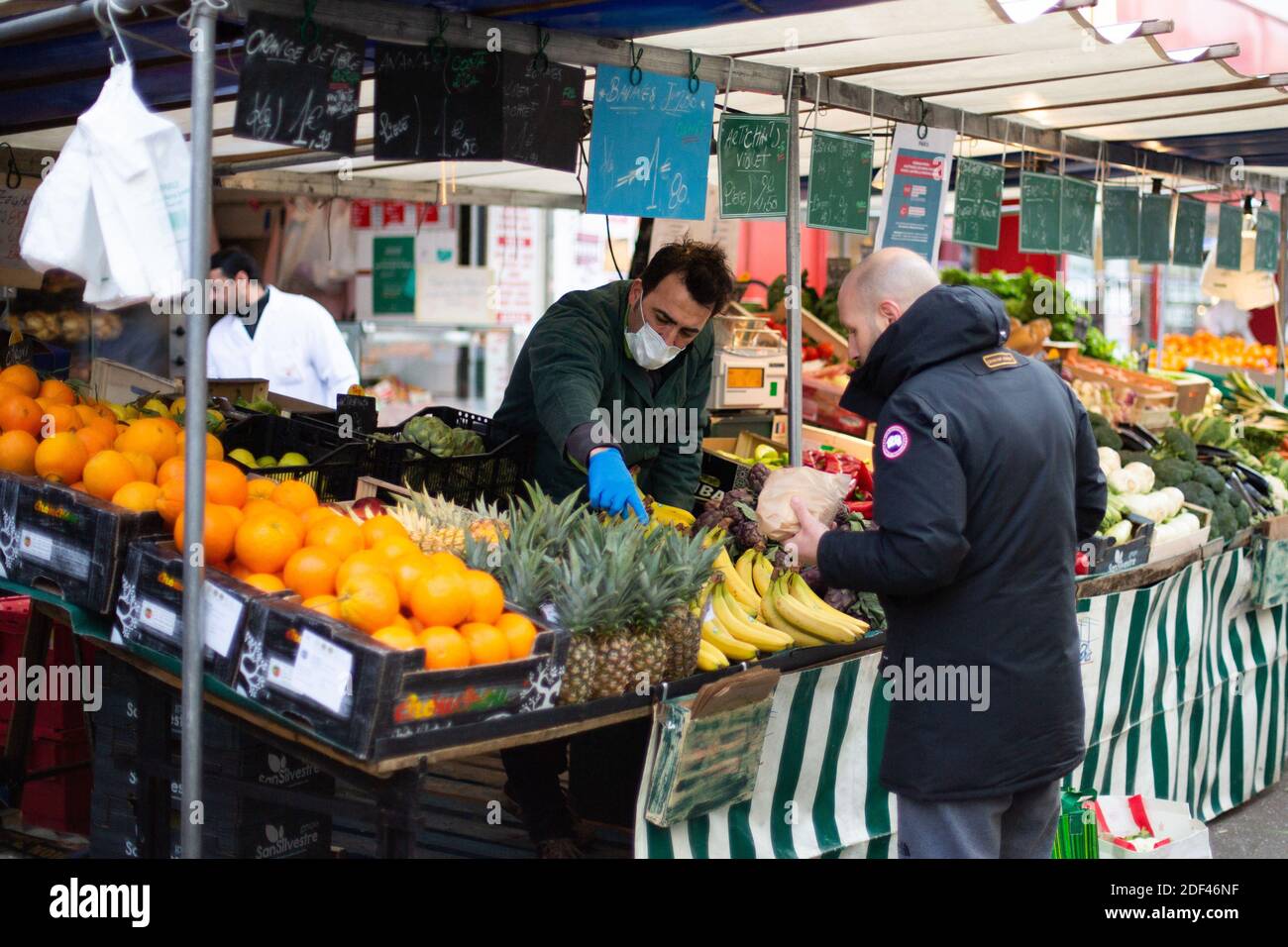 Les gens portant des masques faciaux pour des mesures de protection font leurs courses d'épicerie au marché d'Aligre ( Marche d'aligre ) à Paris le 22 mars 2020 le sixième jour d'un verrouillage strict en France visant à freiner la propagation de COVID-19, le nouveau coronavirus. Un verrouillage strict exigeant que la plupart des Français restent chez eux est entré en vigueur à midi le 17 mars 2020, interdisant toutes les sorties, sauf essentielles, afin de freiner la propagation du coronavirus. Le gouvernement a déclaré que des dizaines de milliers de policiers patrouillaient dans les rues et émettaient des amendes de 135 euros (150 dollars) pour des personnes sans un compte écrit Banque D'Images