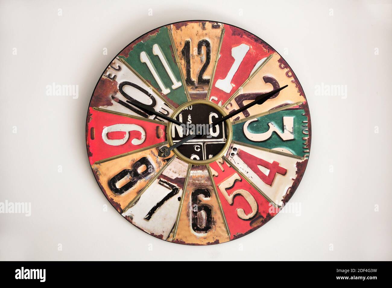 L'horloge avec le visage de métal vintage sur le mur blanc, se référant à la conception des années 1930-50s, avec des chiffres et des secteurs de différentes couleurs Banque D'Images