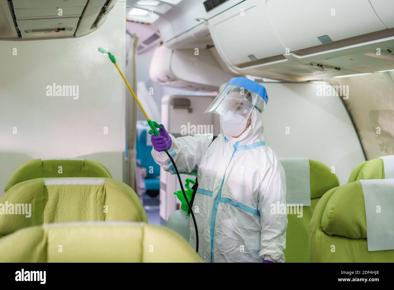Personnel d'une compagnie aérienne en costume de protection (EPI) portant  un visage médical spray désinfectant pour masque pour covid-19 ou  coronavirus dans la cabine d'avion après ou befor Photo Stock - Alamy
