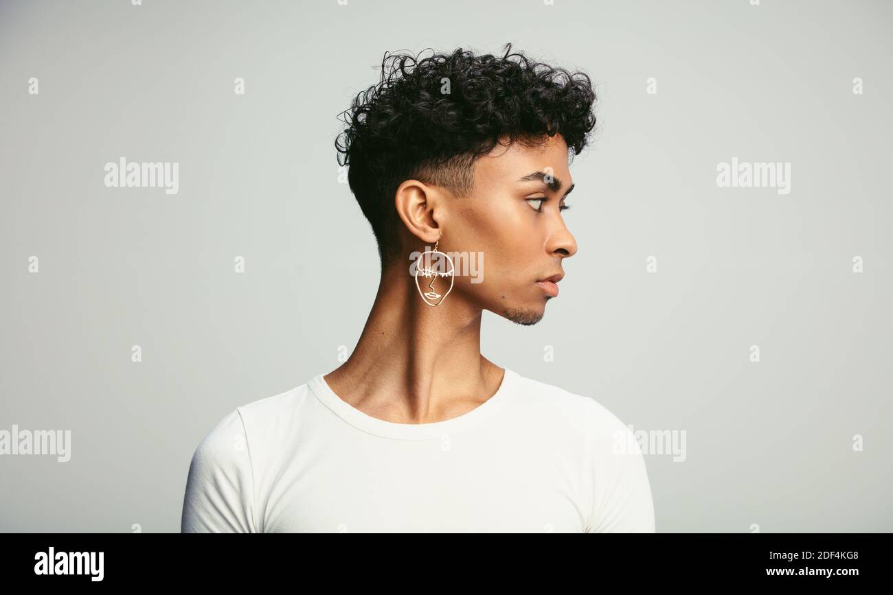 Photo de profil d'un homme de sexe fluide portant un contour d'oreille. Jeune homme androgyne sur fond blanc. Banque D'Images